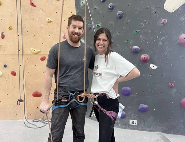 Two climbers in harnesses smiling together at the centre